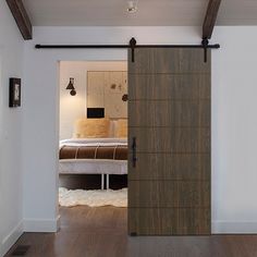 an open door leading to a bedroom with a bed in the background and wooden flooring