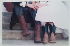 two people sitting on the steps wearing cowboy boots and dress clothes with their hands together