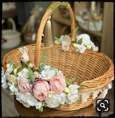 a wicker basket with flowers and a bunny figurine in the center on a table