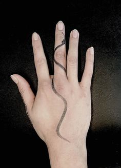 a person's hand with a tattoo on it and a snake drawn on the wrist