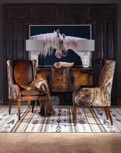 two chairs and a table with a horse painting on the wall