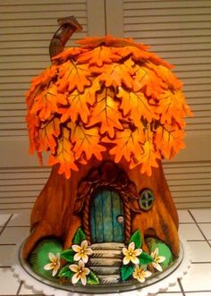 a cake decorated with leaves and flowers on top of a table next to a wall