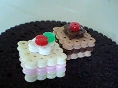 there are two small pieces of cake made out of plastic beads on top of a black doily