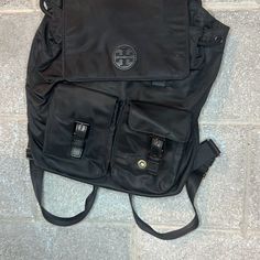 Tory Burch Virginia Drawstring Flap Backpack Black Top Handle, 3.2" Drop Adjustable Shoulder Straps Dimensions: 10.8"L X 5.2"D X 13.4"H Top Drawstring And Snap Flap Closures Two Exterior Magnetic Snap Pockets With Faux Buckle Details, Two Exterior Side Water Bottle Pockets, One Exterior Back Zip Pocket One Interior Front Slip Pocket Lined Tory Burch Virginia Bag, Flap Backpack, Tory Burch Bags, Black Backpack, Black Top, 4 H, Shoulder Straps, Top Handle, Tory Burch