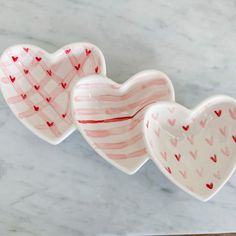 three heart shaped dishes sitting on top of a marble countertop next to each other