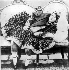 an old black and white photo of a woman sitting on a couch