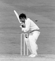 a black and white photo of a man playing cricket with a ball in the air