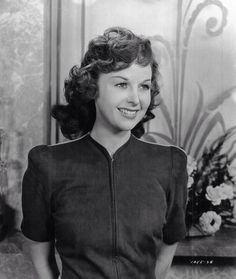 an old black and white photo of a woman in a short sleeved shirt smiling