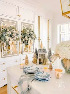 a white table topped with plates and vases filled with flowers