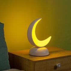 a lamp that is sitting on top of a wooden table in front of a yellow wall