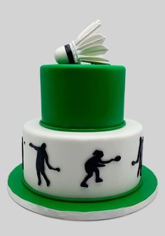 a green and white cake with black silhouettes on the top, holding a badminton racket