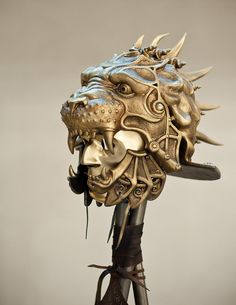 a golden mask with horns and spikes on it's head sits atop a metal pole