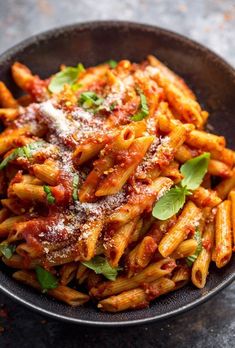 a bowl filled with pasta covered in sauce and parmesan cheese