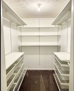 an empty walk in closet with white shelves and clear drawers on the bottom shelfs