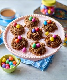 a plate with cookies and candy balls on it next to a cup of cocoa milk