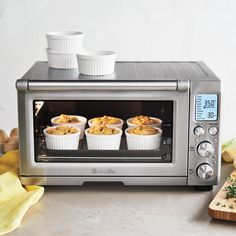 two cups are sitting on top of a toaster oven with food in it and banana peels next to it