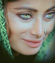 a close up of a person with blue eyes and green scarf around her head, smiling at the camera