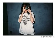 a person taking a photo with a camera in front of a wall and wearing a t - shirt