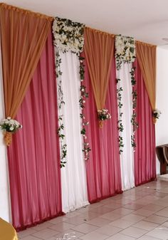 the room is decorated with pink and white drapes, floral arrangements, and gold chairs