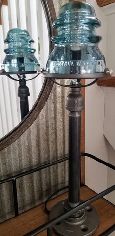 two blue glass lamps sitting on top of a wooden table next to a mirror and stairs