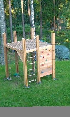 a wooden climbing wall in the middle of some grass