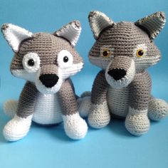 two crocheted stuffed animals sitting next to each other on a blue tablecloth