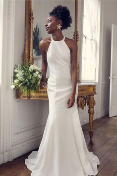 a woman standing in front of a mirror wearing a white dress