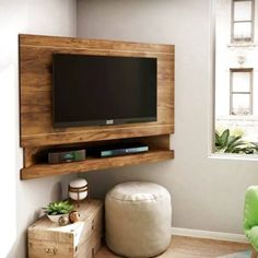 a flat screen tv mounted to the side of a wall in a living room next to a green chair