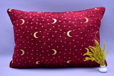 a red pillow with gold stars and crescents on it next to a white golf ball