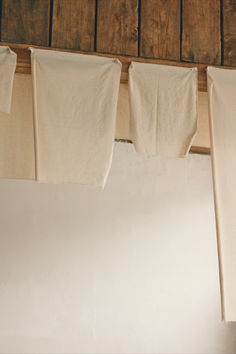 several pieces of cloth hanging on a clothes line in front of a wooden wall and ceiling