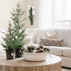 a living room with white couches and christmas decorations on the coffee table in front of it