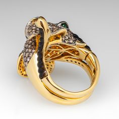 This stunningly crafted 18k yellow gold and black rhodium ring features an elephant wrap design that is pavé set with two-hundred sixty-three (263) round brilliant cut champagne diamonds. The ears are lined with a total of sixty-one (61) bead set round brilliant cut diamonds. The eyes are each channel set with one (1) round modified brilliant cut tsavorite garnet. The top and bottom of the trunk is accented with black Mother-of-pearl carvings. The ring measures 36.4mm at the top, rises 12.6mm ab Luxury Gold Snake Ring With Gemstone, Luxury Yellow Gold Emerald Ring With Single Cut Diamonds, Luxury Diamond Snake Ring, Luxury Snake Ring With Diamond Accents, Luxury Yellow Gold Tsavorite Rings, Luxury Yellow Gold Snake Ring With Single Cut Diamonds, Luxury Gemstone Snake Ring For Formal Occasions, Luxury Formal Gemstone Snake Ring, Luxury Emerald Ring With Pave Setting