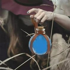 a woman holding a blue and brown flask in her hand