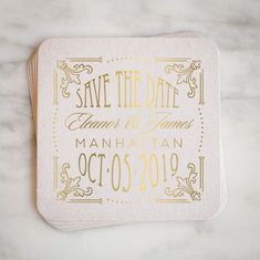 save the date coaster with gold foil on white marble countertop, featuring an ornate design