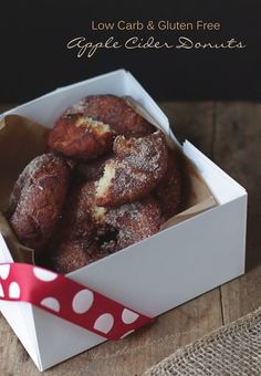 a box filled with donuts sitting on top of a wooden table next to a red and white polka dot ribbon