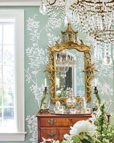 a room with a dresser, mirror and chandelier