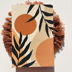 an orange and black art piece on a white background with brown fringes around it