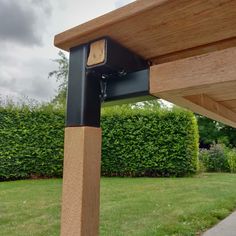 a wooden bench sitting in the middle of a lush green park next to a hedge