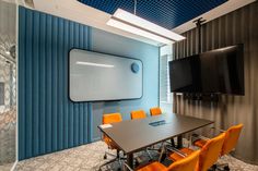 a conference room with orange chairs and a flat screen tv mounted to the wall above it