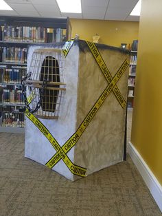 a cardboard structure with caution tape wrapped around it in the middle of a library filled with books