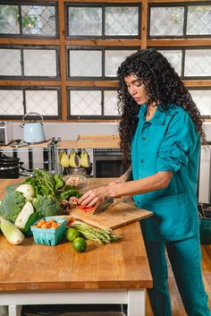 a woman cutting up vegetables on a wooden table