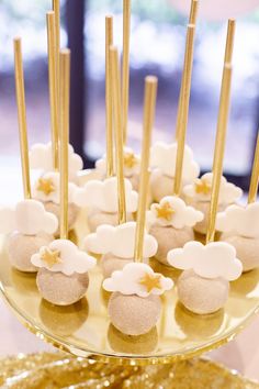 there is a cake with white flowers and gold sticks on the top, along with other desserts