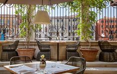 an outdoor dining area with tables and chairs, potted plants on the railings