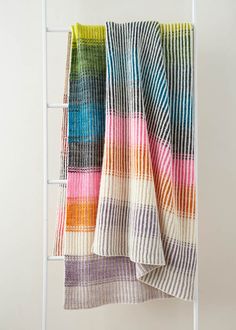 multicolored striped blanket hanging on white ladder