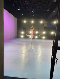 a woman is dancing on a stage with lights in the back ground and behind her