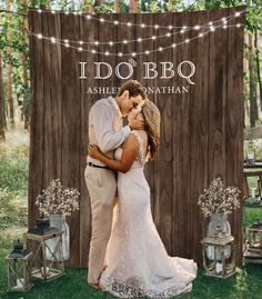 a bride and groom kissing in front of a wooden backdrop for their outdoor wedding ceremony