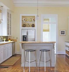 a kitchen with two stools in front of the island and an oven on the other side