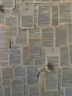 several pieces of paper with flowers pinned to them on a wall covered in old books