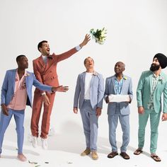 a group of men standing next to each other in front of a white wall holding flowers