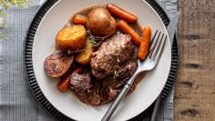 a plate with meat, potatoes and carrots on it next to a knife and fork